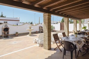 Une terrasse extérieure agrémentée d’une colonne en briques, d’une fontaine en pierre et d’une table dressée pour le repas.