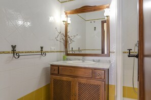 Une salle de bain avec un meuble-lavabo en bois, un miroir, un évier et un espace douche.