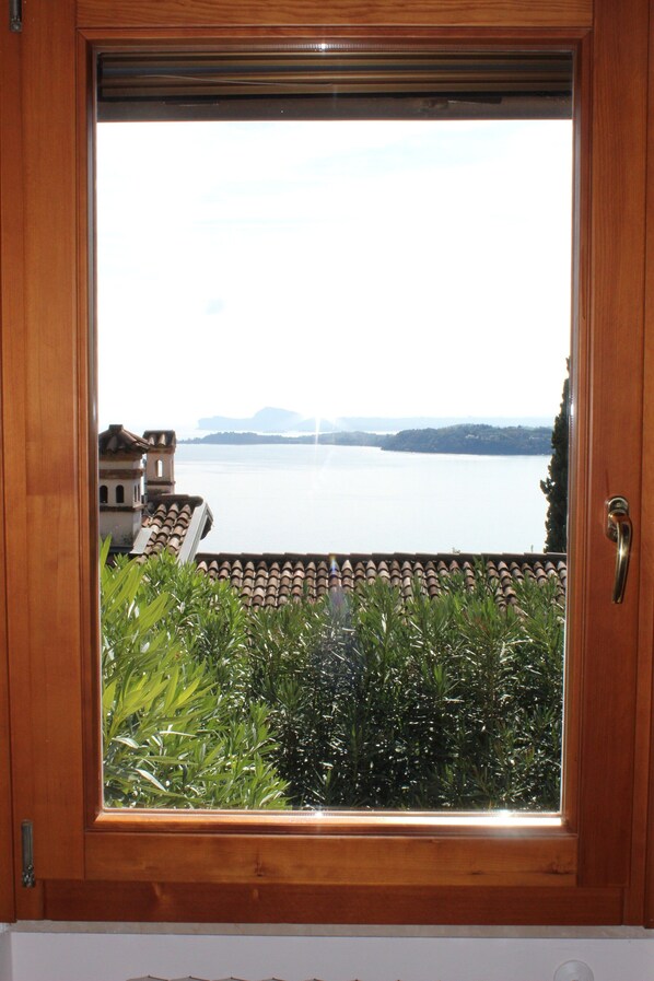 A wooden-framed window with a view of a lake and distant mountains. - Charming Villa Belvedere with View of Lake Garda (gardone-riviera)