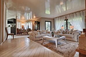 A spacious living area with a sofa set, a coffee table, and a dining table with chairs.