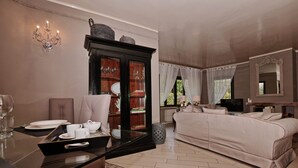 Una habitación con una mesa de comedor, un sofá, un aparador con puertas de vidrio, una araña y un televisor.