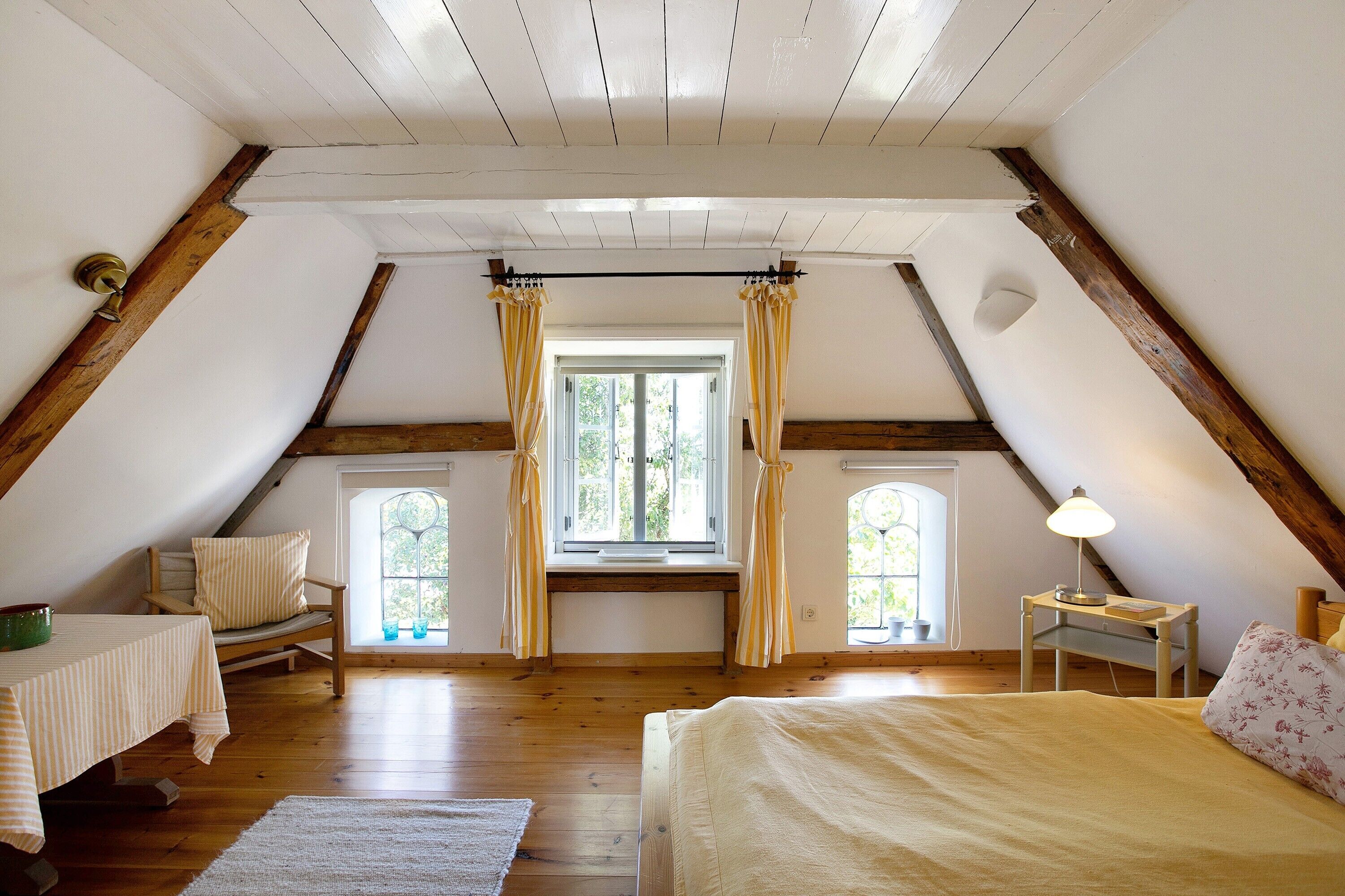 A bedroom with a bed, a desk, a chair, and a window with curtains.