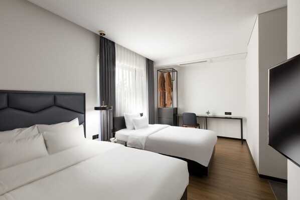 A hotel room with two beds, a desk, a chair, a TV, and a large window with curtains. - Neulpum Hotel (Jeonju)