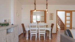 A dining area with a table, chairs, and a hanging light fixture.
