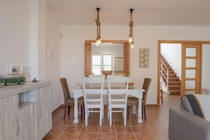 A dining area with a table, chairs, and a hanging light fixture.