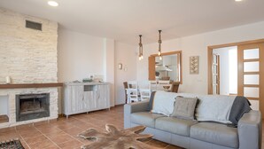 A living room with a fireplace, a sofa, a coffee table, and a dining area with chairs.