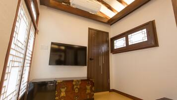 Quarto com teto de madeira, televisão integrada, guarda-roupa e janela com padrão quadriculado.