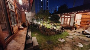 Une cour de style japonais traditionnel, avec des lanternes en pierre, un banc en bois et un petit arbre.