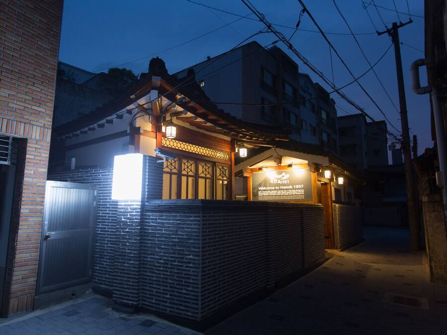 A traditional Japanese building with a wooden facade, a signboard, and a brick wall.