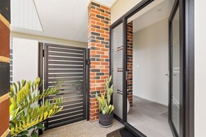 Enter a serene space through the sliding glass door, surrounded by a potted plant and a black metal gate.