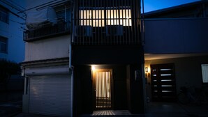 A residential building at dusk with a lit entrance and a covered balcony. - Casa Grapp Tengachaya II (Osaka)