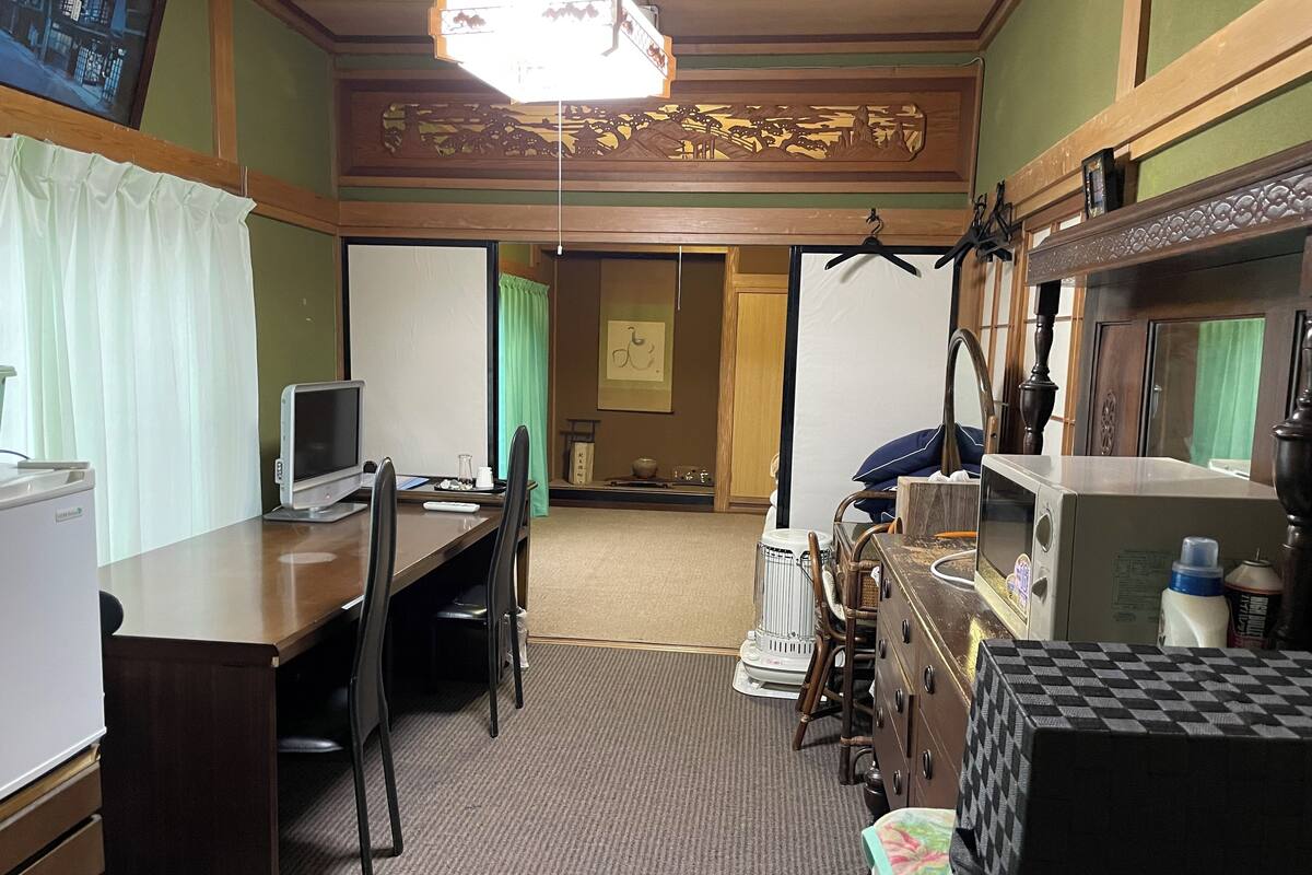Een hotelkamer met een bureau, stoel, bed en uitzicht op de straat.