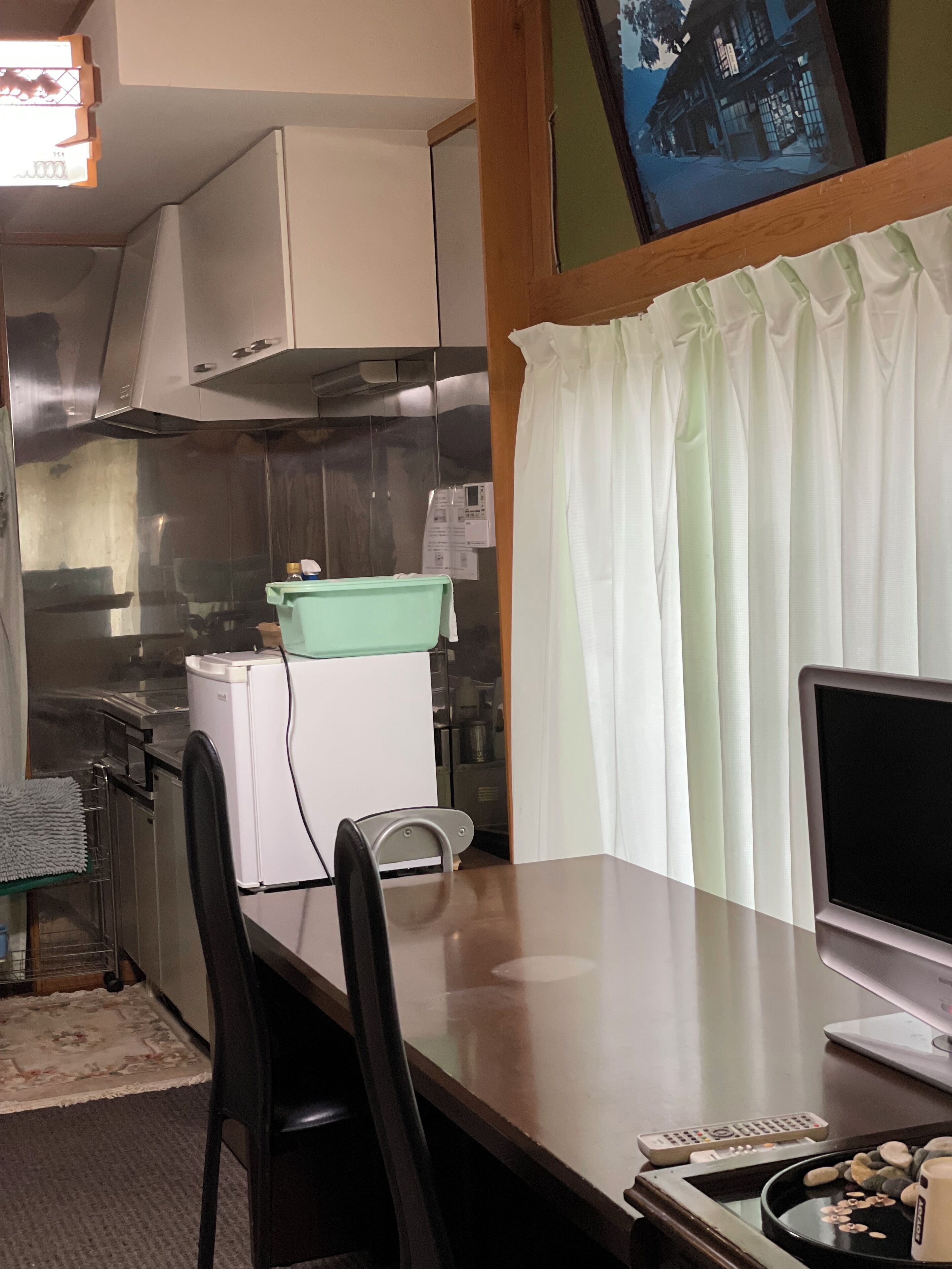 A compact kitchen with a dining area, including a table, chairs, and a TV.