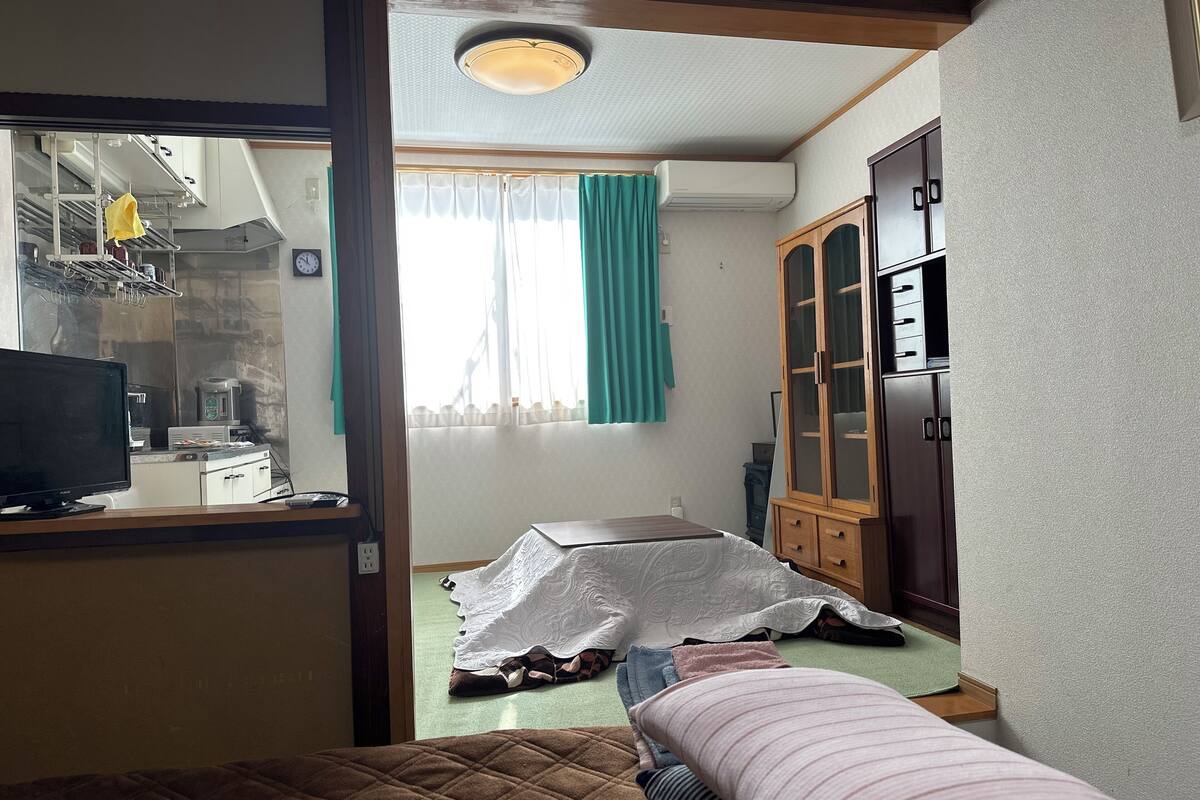 Een slaapkamer met een bed, een houten garderobe, een bureau met een computer en een raam met gordijnen.