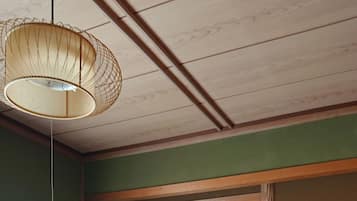 A room with a wooden cabinet, a hanging lamp, a green curtain, and a framed picture on the wall.