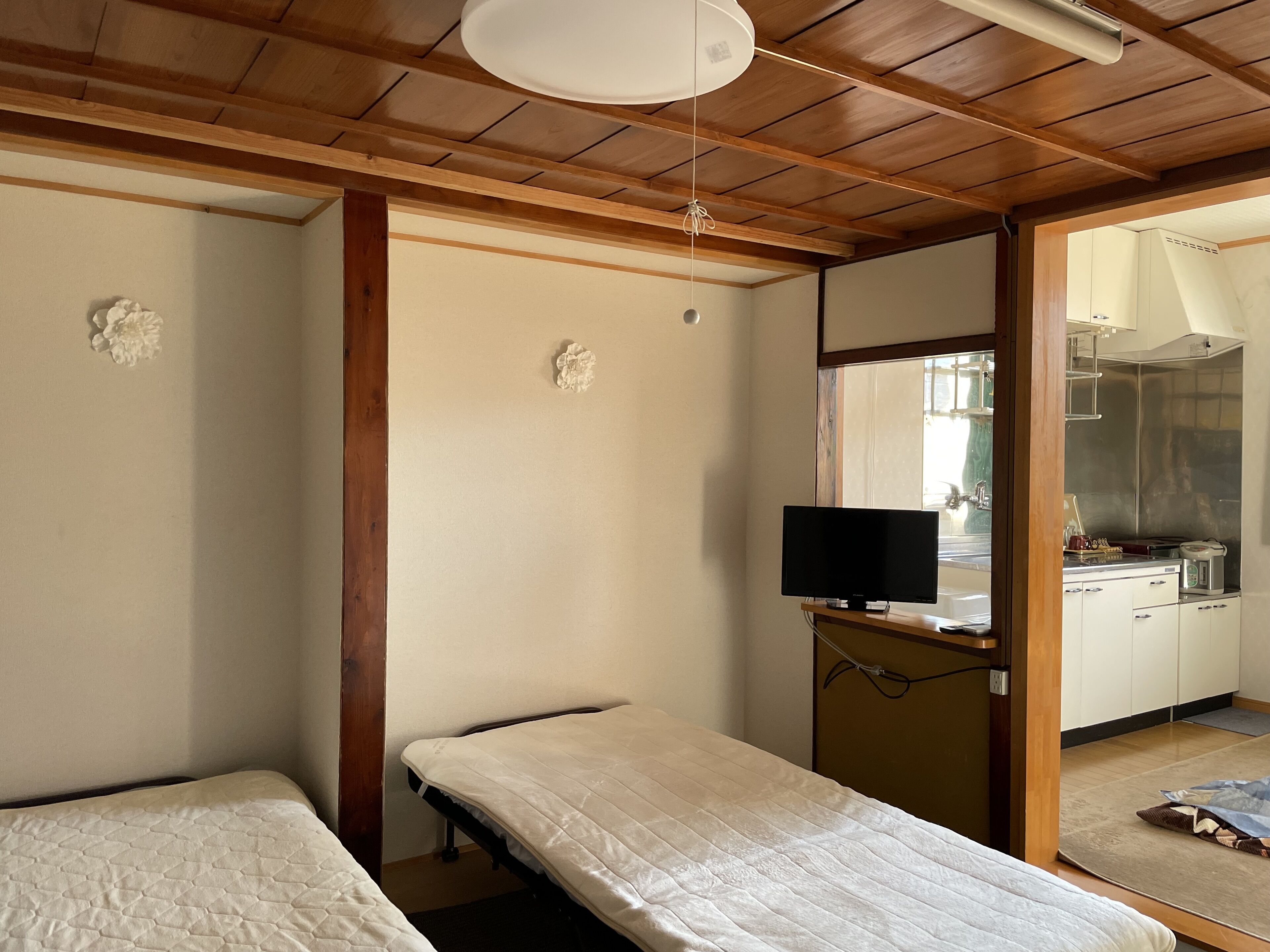 A room with two beds, a television, and a kitchenette.