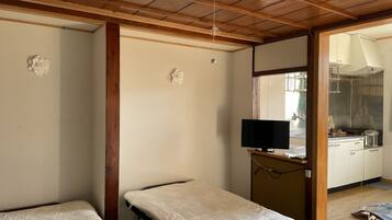 A room with two beds, a television, and a kitchenette.