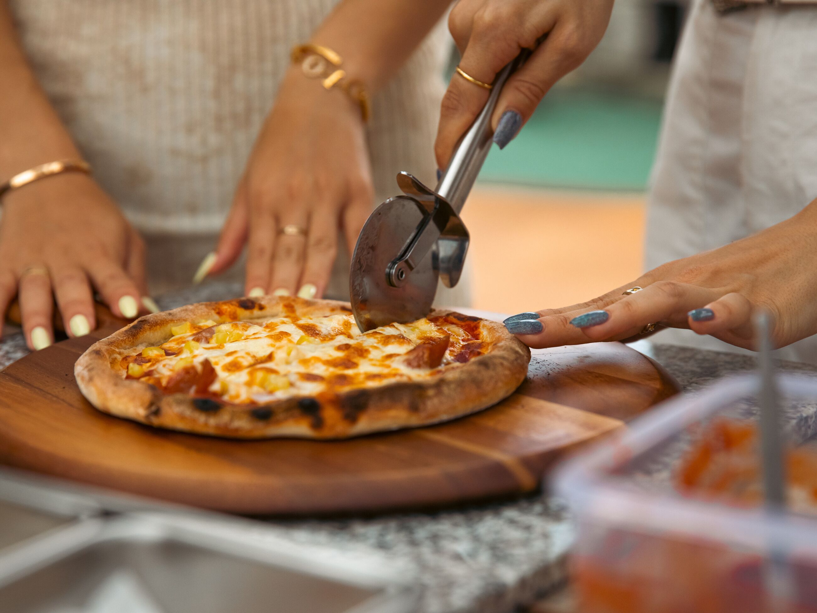Una pizza siendo cortada sobre una tabla de madera.