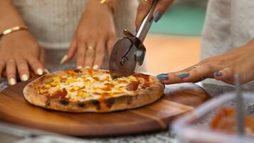 Una pizza siendo cortada sobre una tabla de madera.