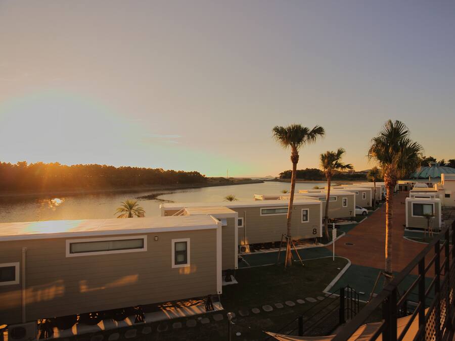 A row of RVs with a river and trees in the background.