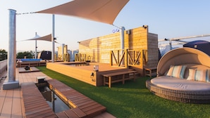 Une terrasse sur le toit avec une piscine, des sièges extérieurs et un grand auvent.
