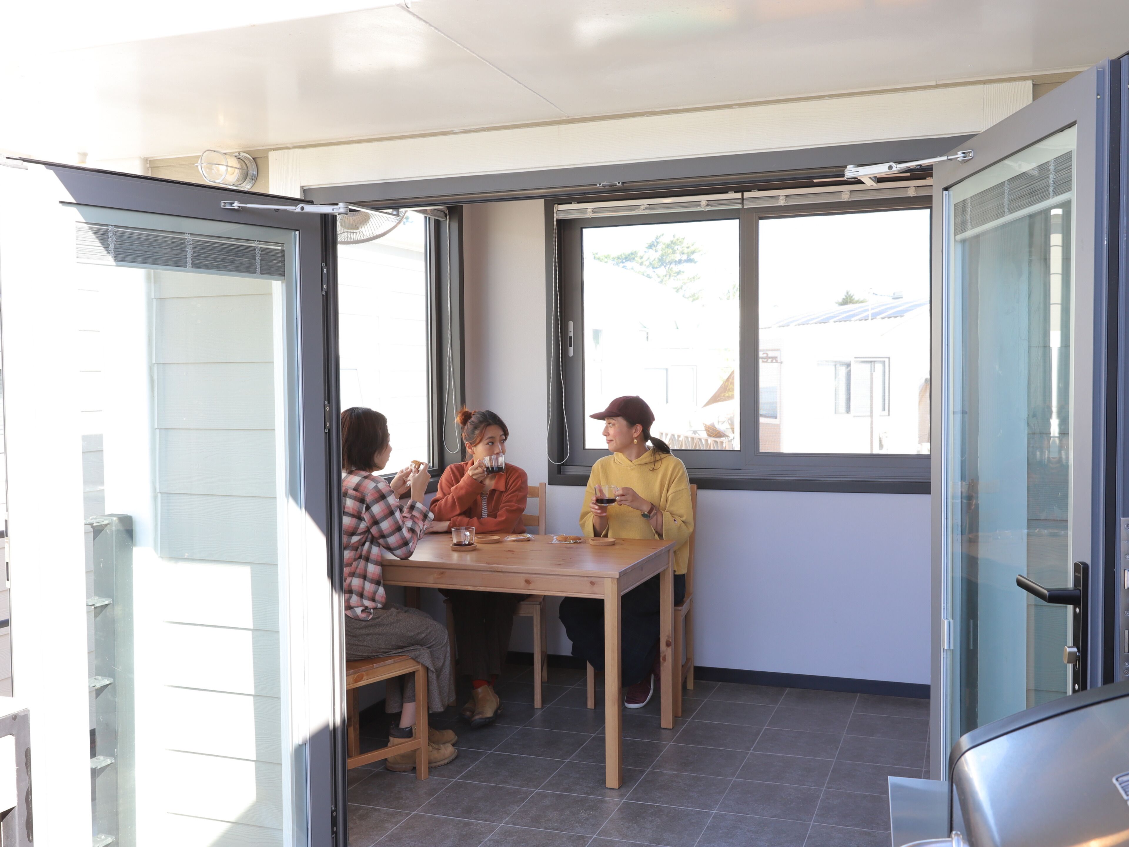 Una habitación pequeña de concepto abierto con una mesa y sillas de madera, ventanas amplias y un gran ventanal corredero.