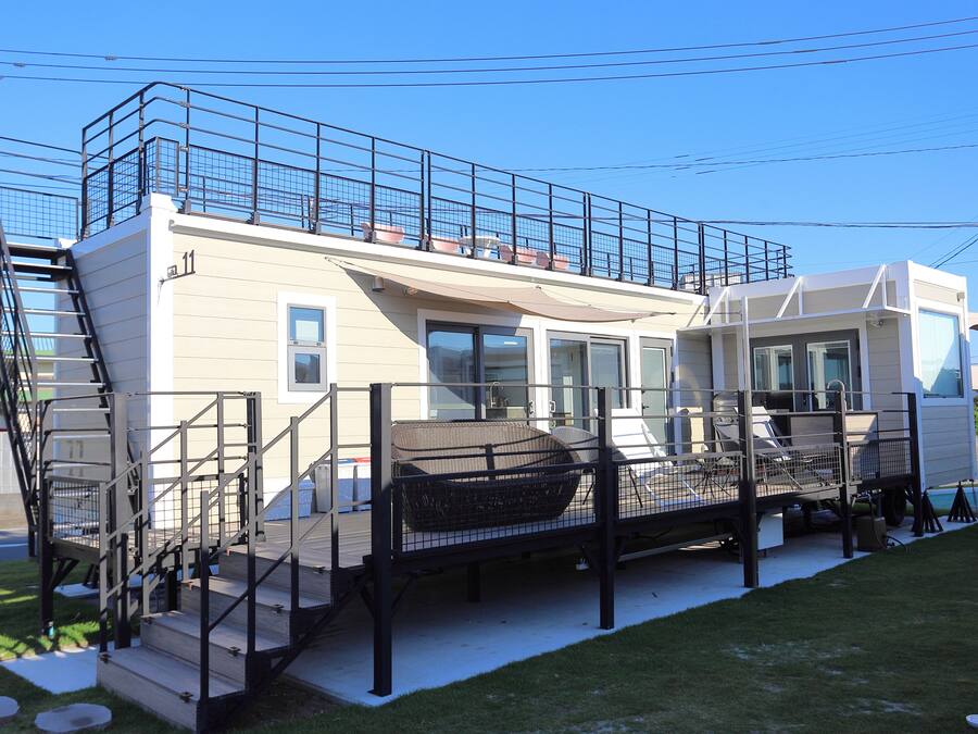 A modern house with a balcony, a staircase, and a covered outdoor seating area.
