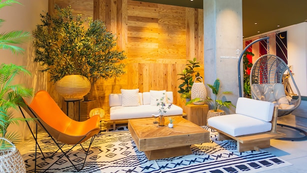 Un espace de détente moderne avec un mur en bois, un fauteuil suspendu, un ensemble de canapés et une table basse.