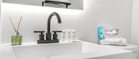 Un baño moderno con un lavabo blanco, un grifo negro y un espejo encima.