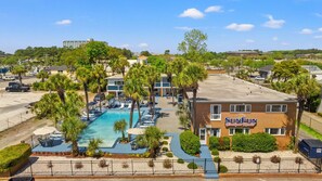 Un hotel con piscina, palmeras y un letrero que dice 'SunFun Boutique Motel'.