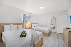 Habitación de hotel con dos camas, un armario de madera, un espejo y una ventana con cortinas.