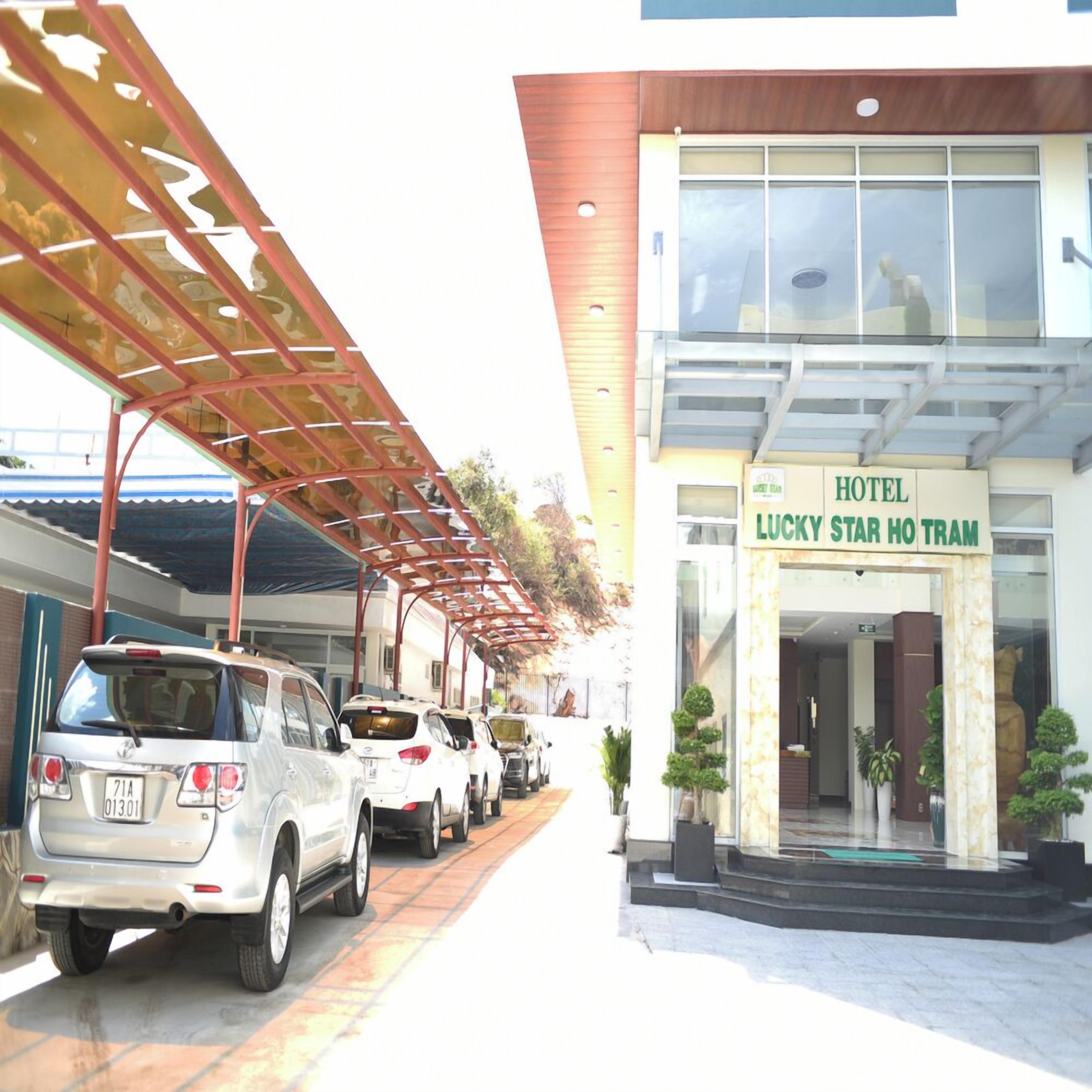 A hotel entrance with a covered parking area and several parked cars.