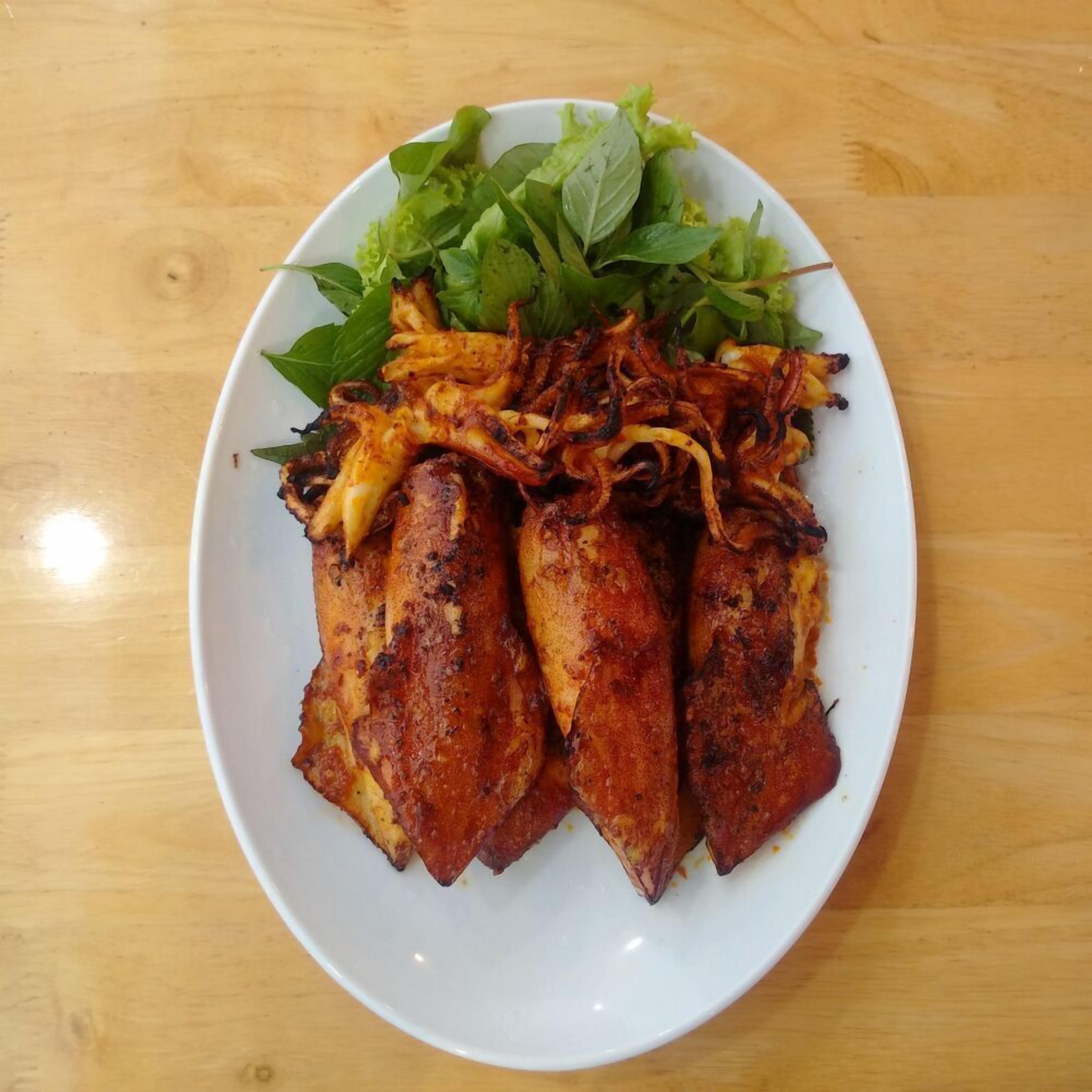 Une assiette de poulet grillé accompagné de légumes, posée sur une table en bois.