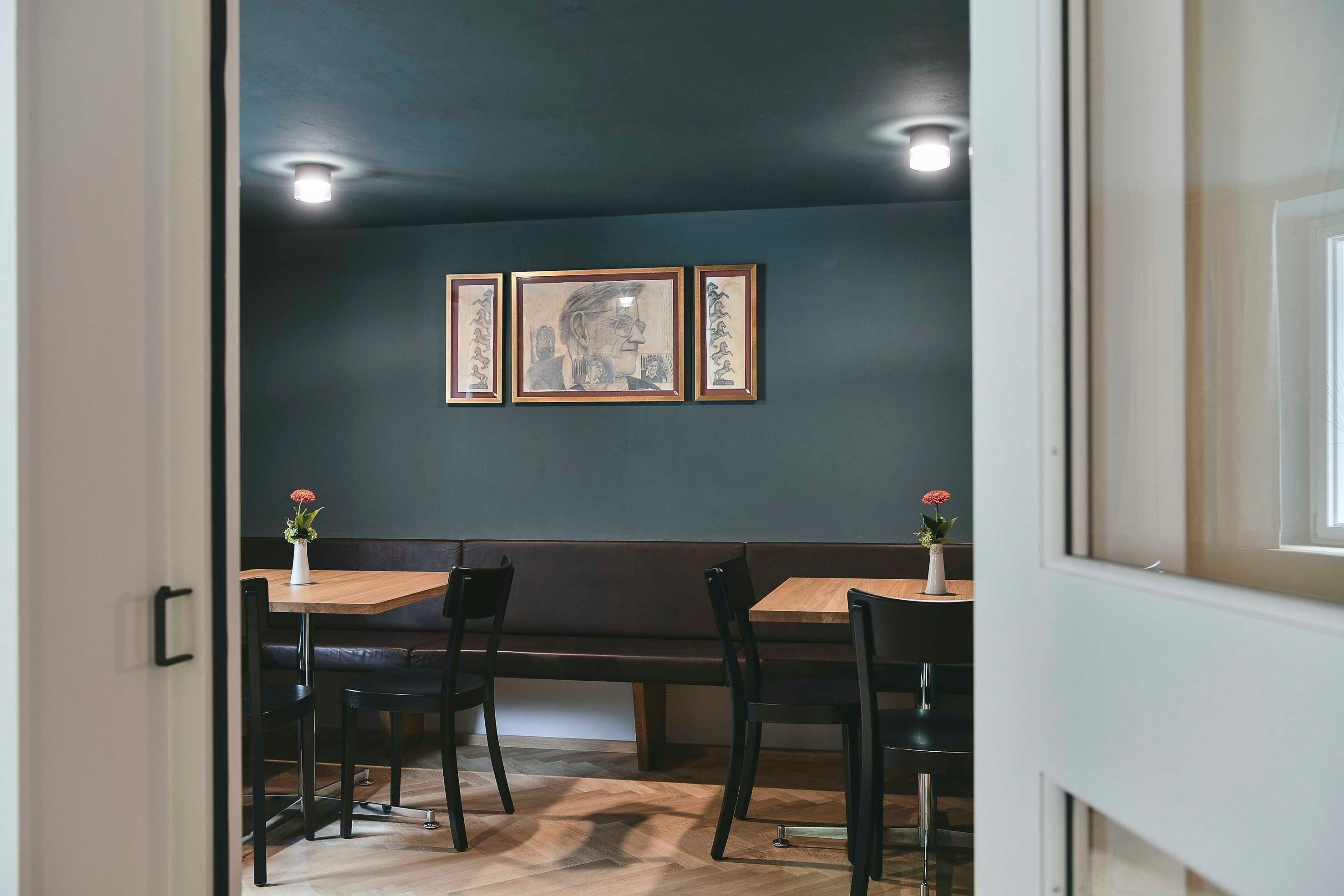 A dining area with a wooden table and chairs, a bench, and framed artwork on the wall.