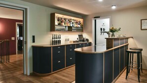 A modern kitchen with a bar area, wooden flooring, and a built-in wine rack. - Single room - Gasthof Rössle (Innerbraz)