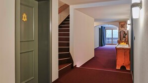 A hallway with a green door, a wooden staircase, and a small wooden table with fruit. - Single room - Gasthof Rössle (Innerbraz)