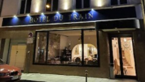 Un hôtel à plusieurs étages, sur lequel on peut lire l’inscription « HÔTEL DU RAIN ».