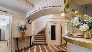 Un hall d’hôtel avec un escalier, un comptoir d’accueil et une horloge.