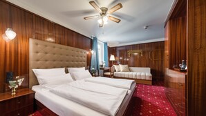 Une chambre d’hôtel avec un grand lit, deux tables de chevet, un ventilateur de plafond et un lambris en bois.