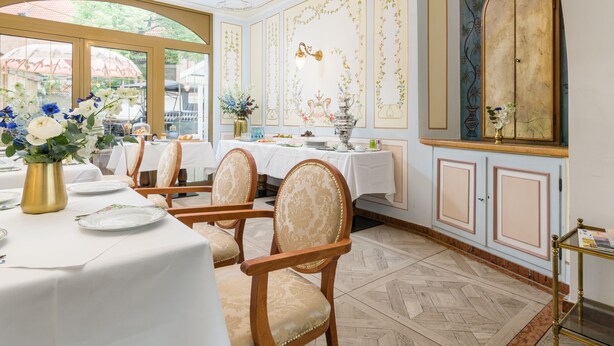 Un coin repas avec une table dressée pour quatre personnes, des chaises dotées de sièges rembourrés, un lustre et un panneau décoratif mural.