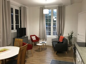 Uma sala de estar moderna com televisão, uma mesa de jantar e um sofá.