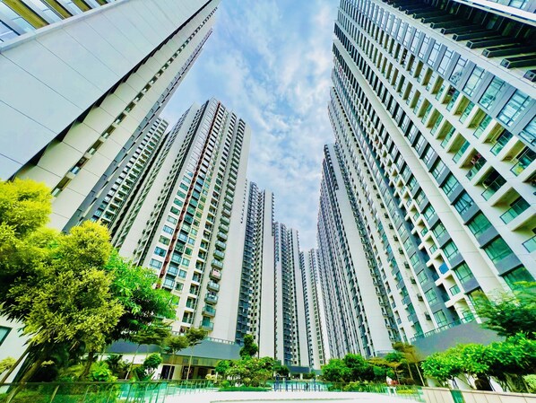 A high-rise residential building with multiple floors, balconies, and a clear sky.