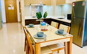 A modern kitchen with a dining table set for two, a refrigerator, and a countertop with a sink and stove.