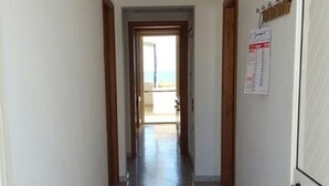 A hallway with a tiled floor leading to a door with a calendar on the wall. - Appartamento Lido Marini (Ugento)