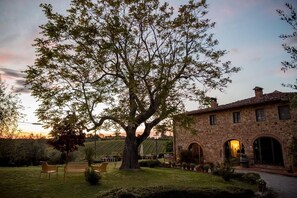 Un edificio in pietra con finestre ad arco e un grande albero sullo sfondo.