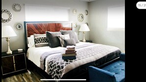 A neatly arranged bedroom with a bed, bedside tables, a chair, and decorative wall mirrors. - CYC Lounge with Guest House (San Antonio)