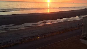 Ein Sonnenuntergangsblick vom Balkon mit Blick auf einen Strand, im Vordergrund eine Straße.