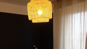 Ein Einzelbett mit weißer Bettwäsche in einem Zimmer mit dunkel gestrichenen Wänden und einer Pendelleuchte.