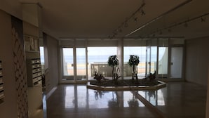 Ein geräumiges Zimmer mit großen Fenstern, Holzboden und einer kleinen Zimmerpflanzenanordnung.