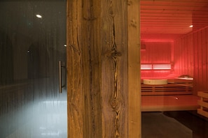 Interior em madeira com parede de vidro, um pilar de madeira e um espaço circular com assentos iluminados por luzes vermelhas.